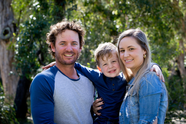 Father, Mother and young son together outdoors in sunlight in park