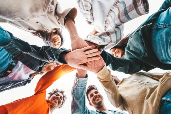 A group of friends in a circle with their hands on top of one another.